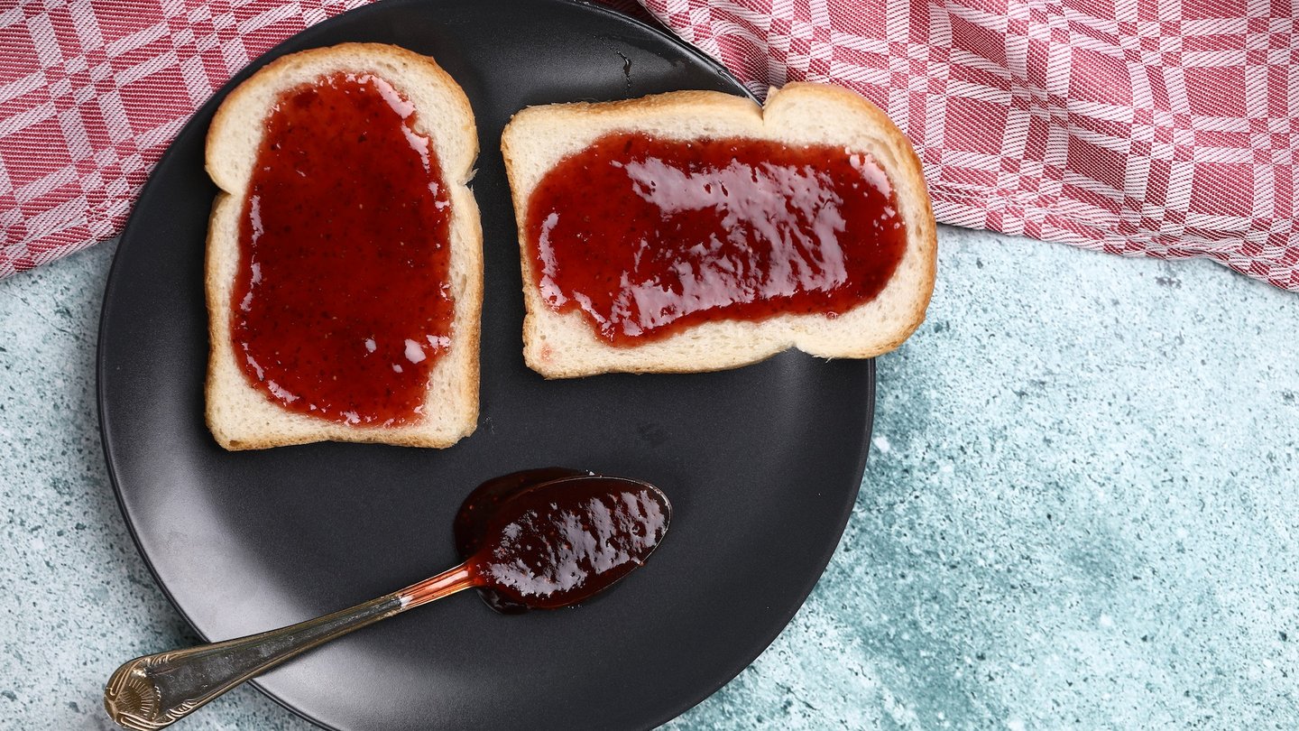 Das Bild zeigt zwei mit Marmelade bestrichene Scheiben Brot.