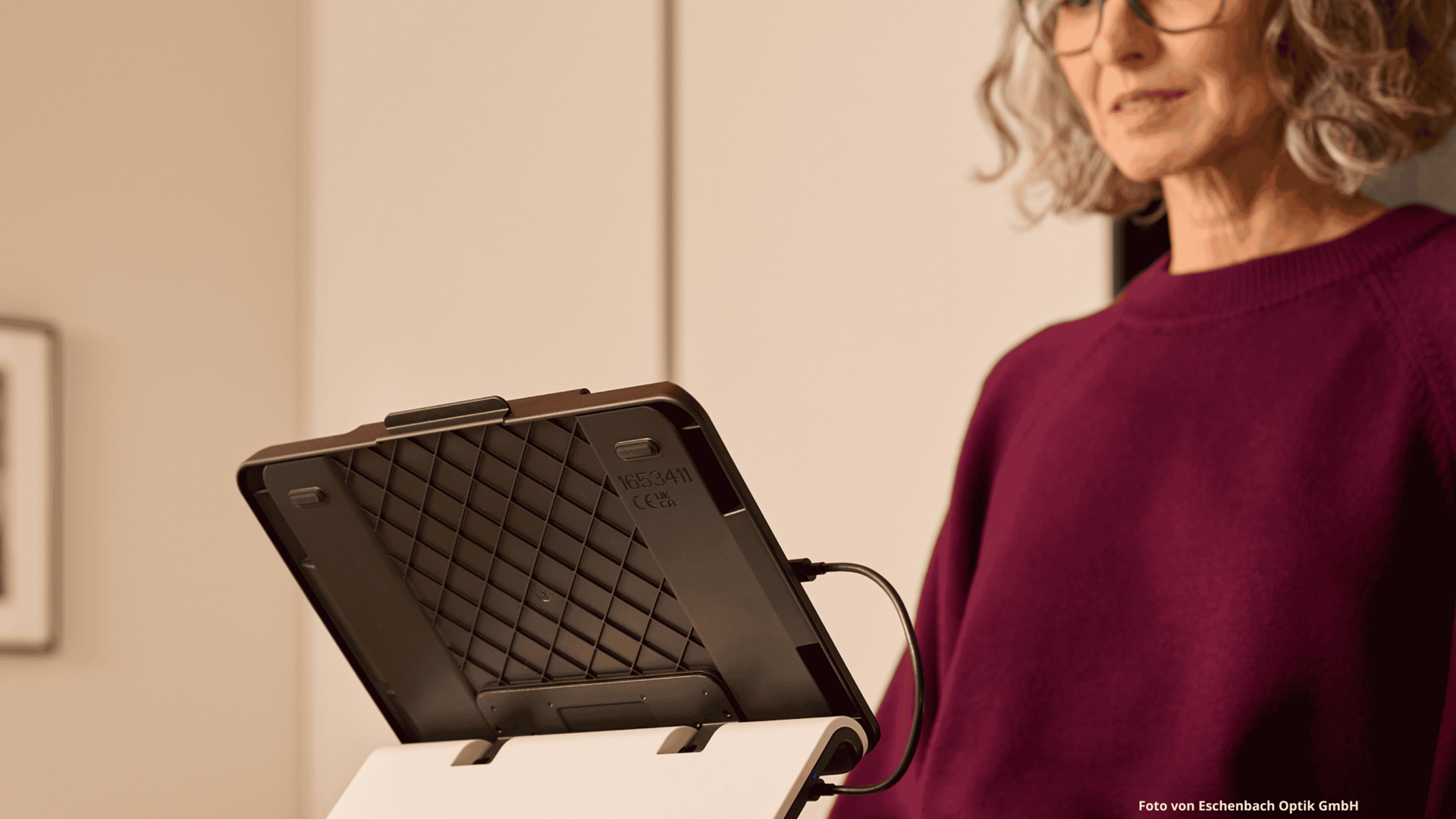 Eine ältere Frau, die in einer Küche steht und ein iPad mit optaro® XL nutzt.