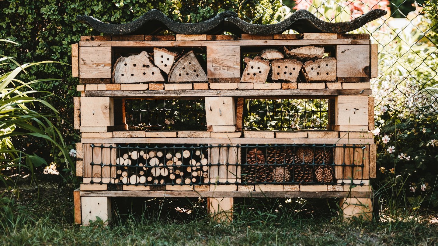 Das Bild zeigt ein Insektenhotel in einem Garten. 