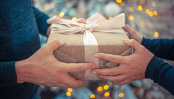 Ein Weihnachtsgeschenk wird von zwei Personen in den Händen gehalten.