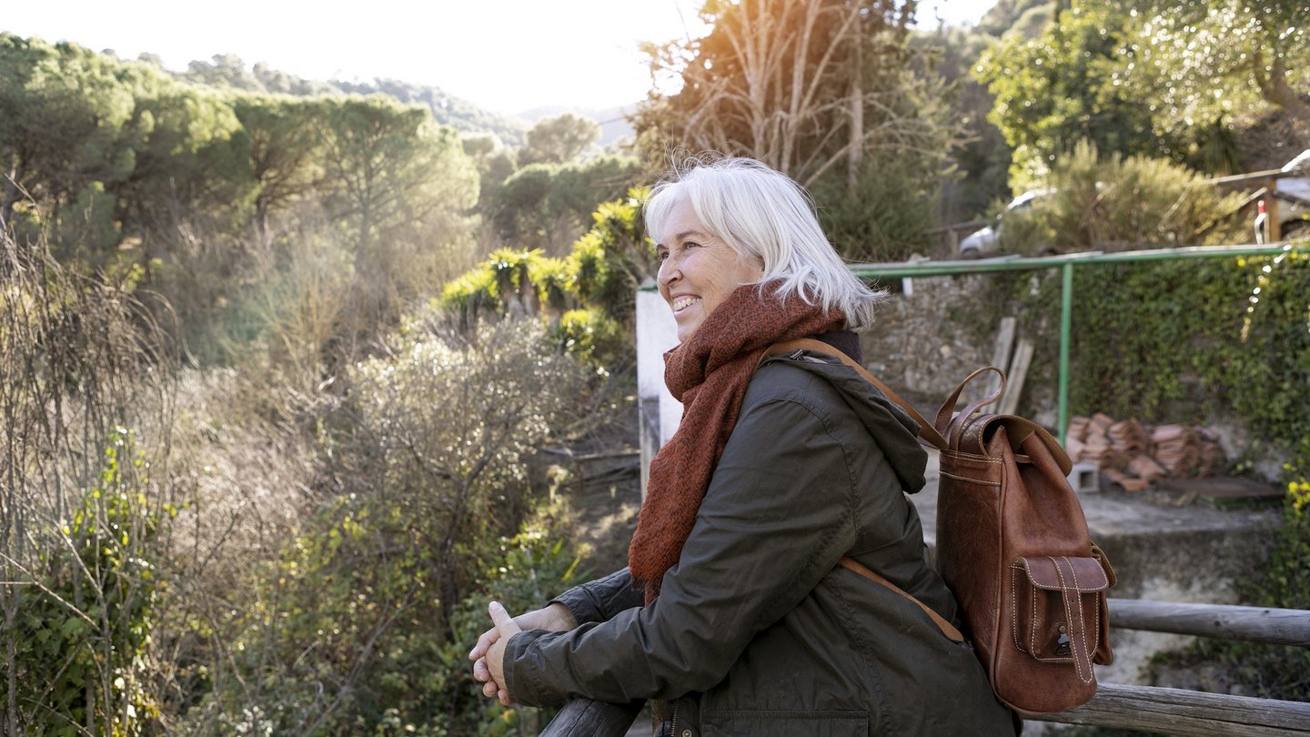 Das Foto zeigt eine Frau, die in der Natur die Aussicht genießt.