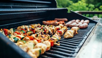 Das Bild zeigt einen Grillrost mit Schaschlik-Spießen und Bratwurst.