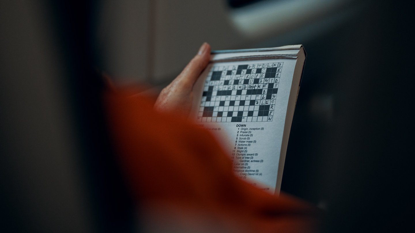 Das Foto zeigt eine Person, die ein Kreuzworträtsel löst. 