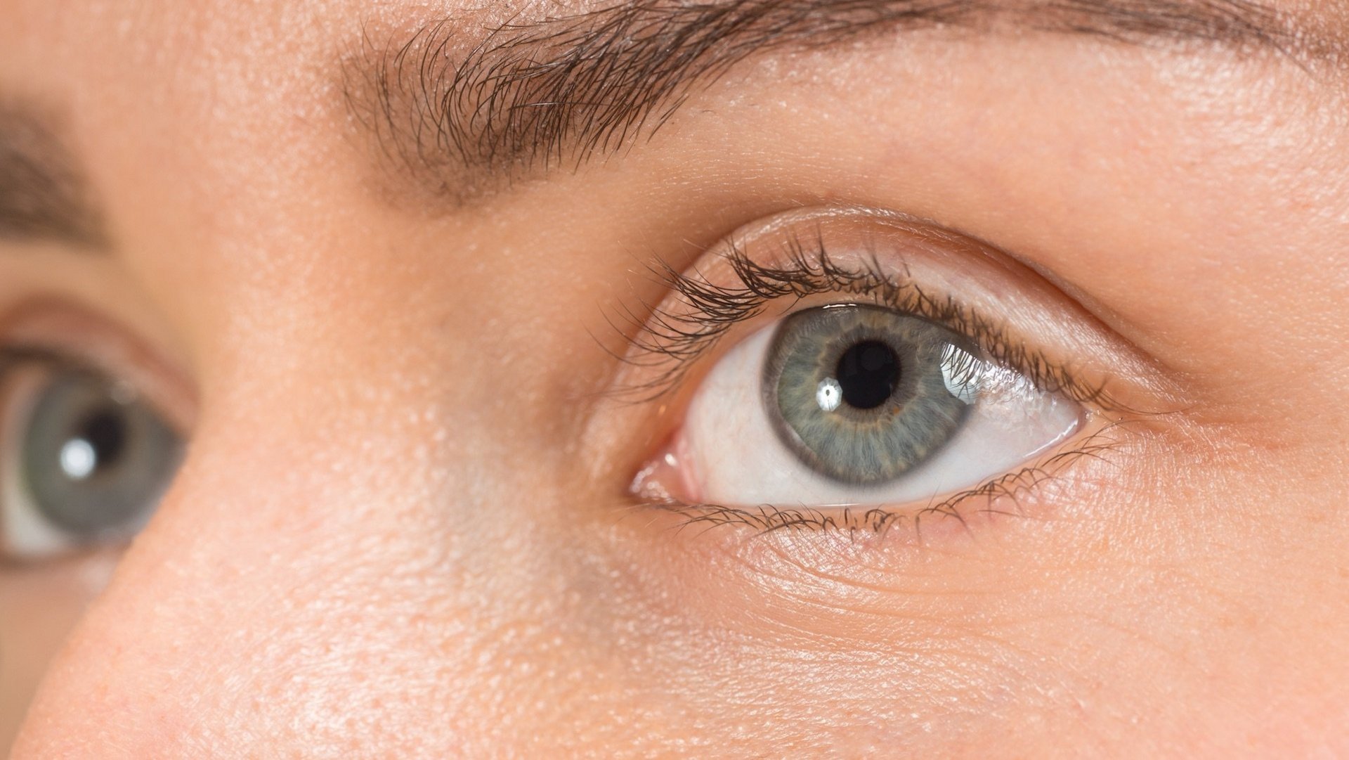Das Foto zeigt eine Person mit grauen Augen in Nahaufnahme. 