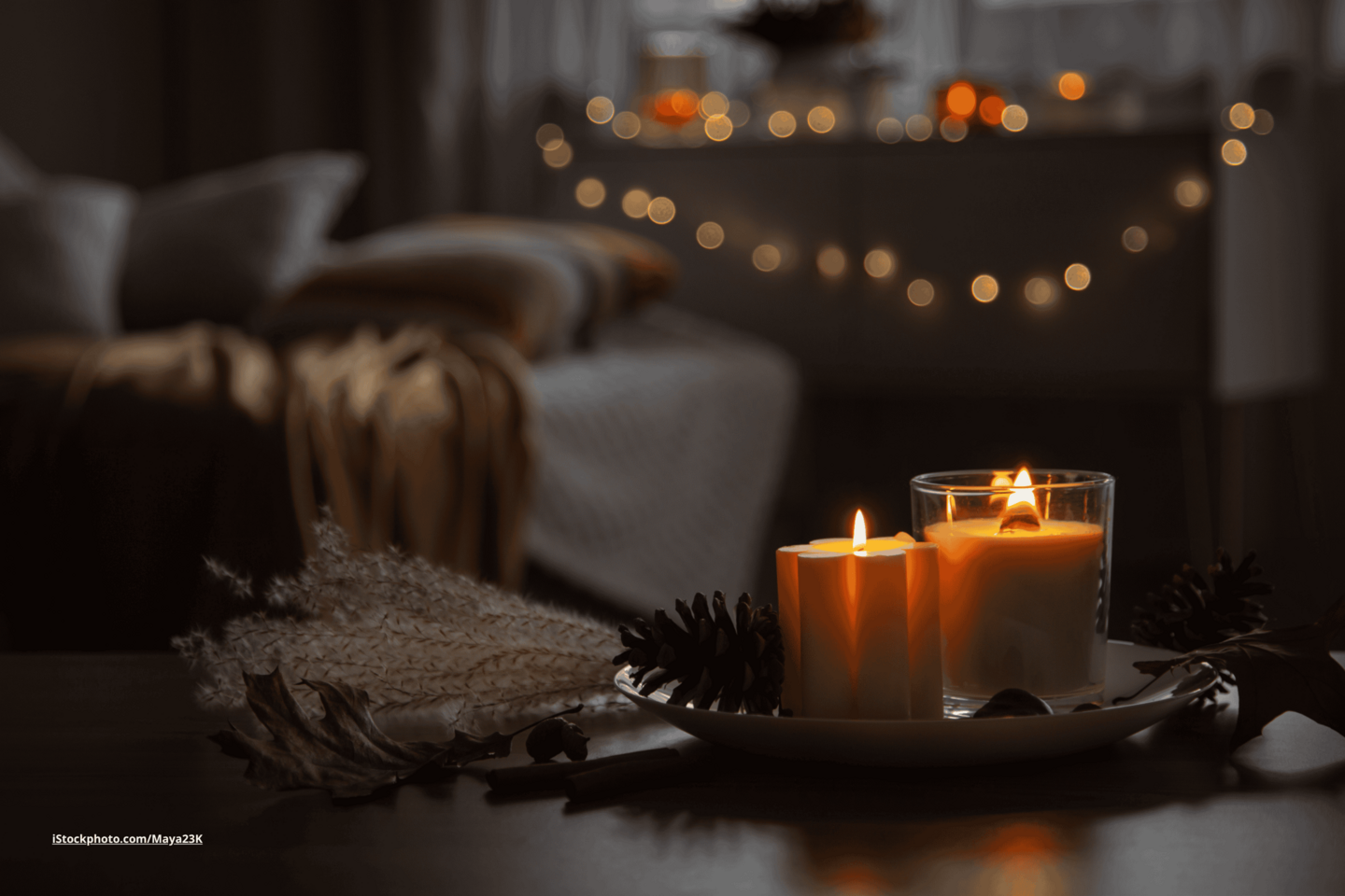 Das Foto zeigt einen Wohnzimmertisch mit Herbstdekoration und gemütlichen Kerzen bei Dämmerlicht.