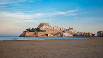 Panoramablick auf die charmante Küstenstadt Peniscola in Spanien, die noch nicht von Touristen überlaufen ist, mit der historischen Festung auf einem Hügel, umgeben von weißen Gebäuden und einer ruhigen Strandpromenade.