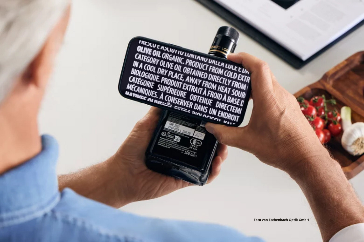 Ein Mann liest mit Hilfe von optaro die Inhaltsangaben auf einer Olivenöl-Flasche. 
