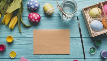 Das Foto zeigt ein Blatt Papier neben einem Pinsel und einer Osterdekoration.