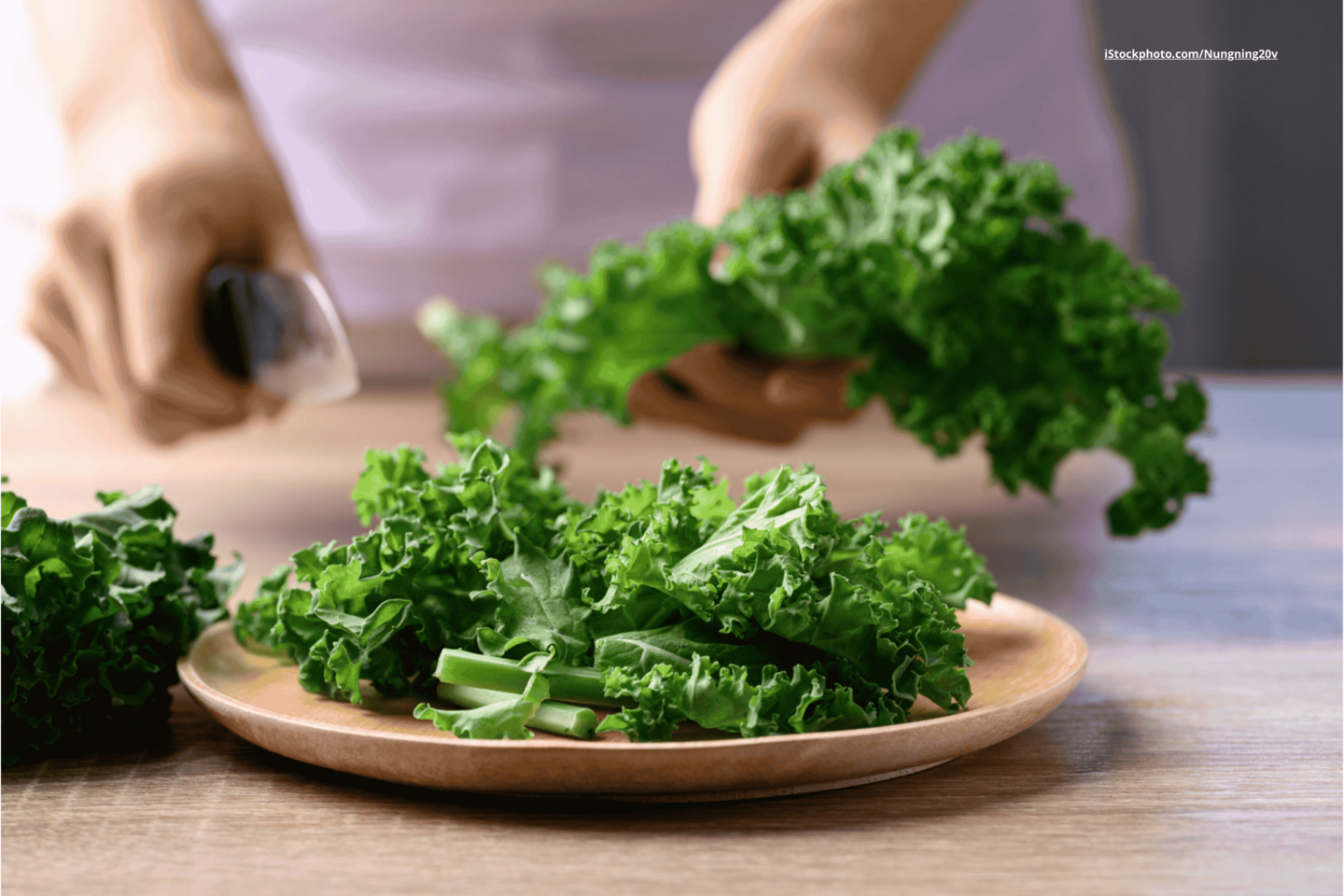 Das Foto zeigt eine Person, die Grünkohl auf einem Brett mit einem Messer schneidet.