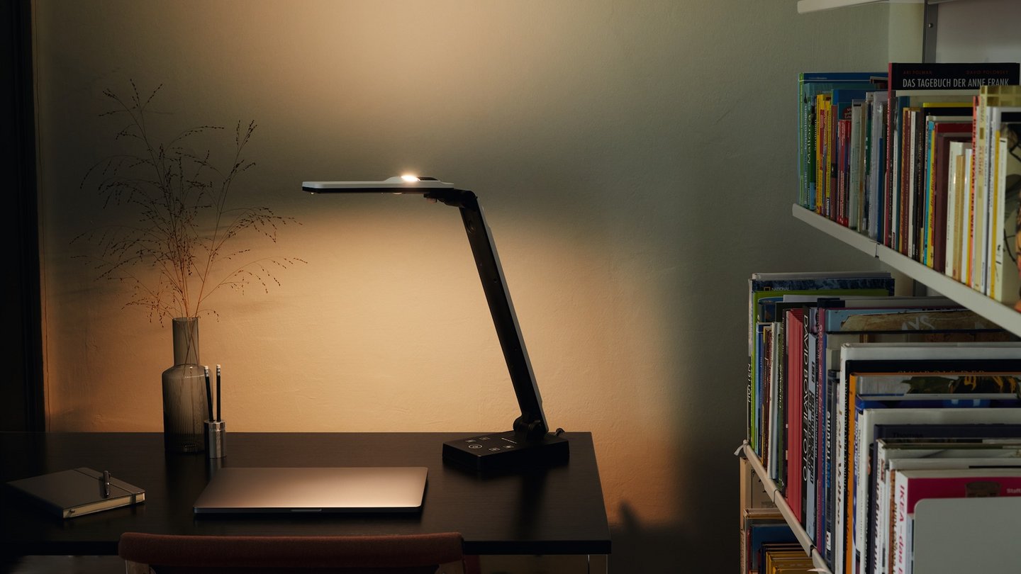 Das Bild zeigt die Tischleuchte elumentis LED auf einem Schreibtisch stehend.