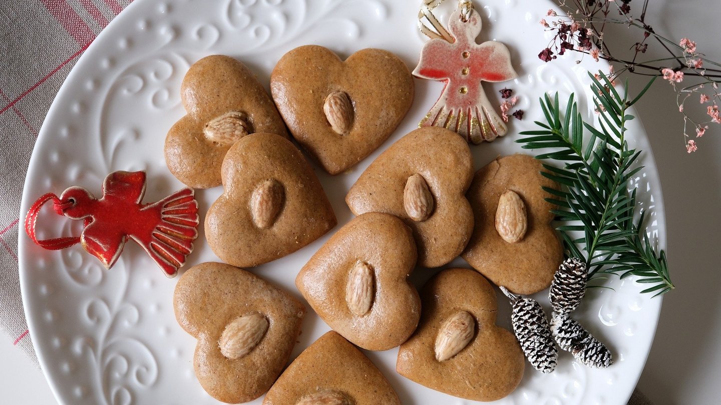 Lebkuchenherzen auf einem Teller mit weihnachtlicher Dekoration.