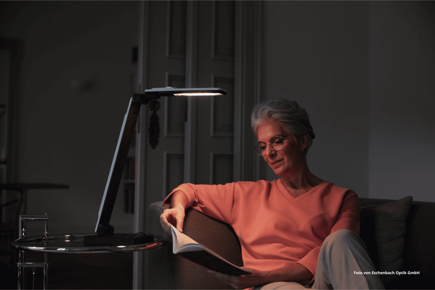 Das Foto zeigt eine Frau, die auf dem Sofa sitzt und unter dem Licht von elumentis® LED ein Buch liest.