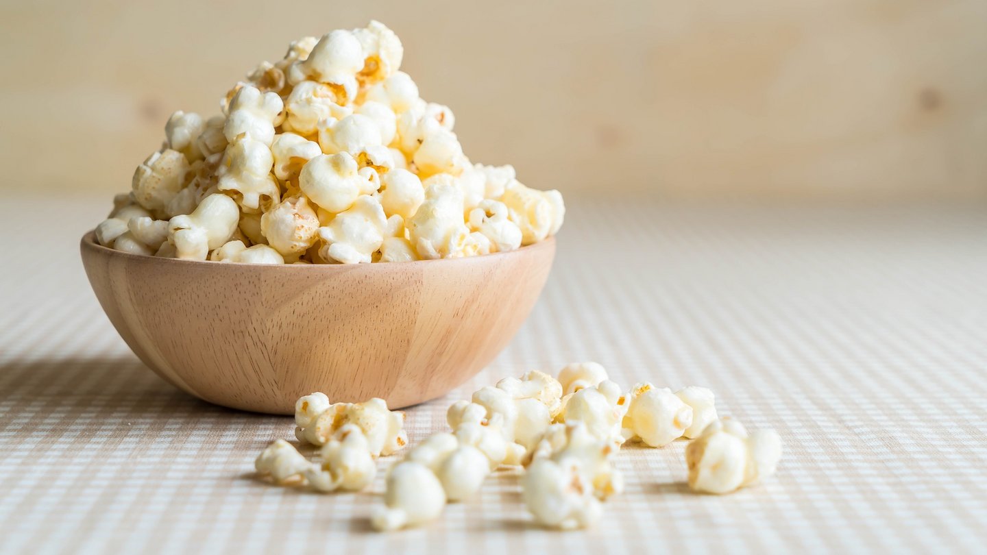 Das Foto zeigt eine Schale voll Popcorn auf einem Tisch.