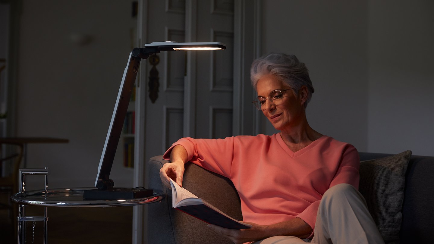 Das Foto zeigt eine Frau, welche ein Buch unter der Lampe elumentis LED liest.